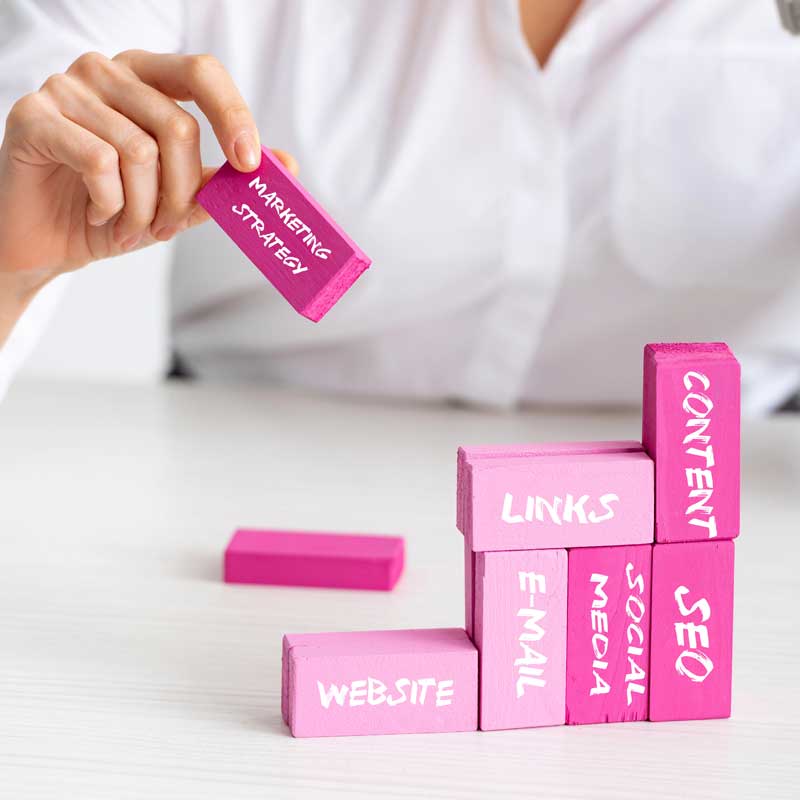 elective focus of businesswoman stacking marketing pyramid with pink building blocks isolated on grey, marketing strategy illustration