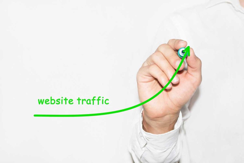 hand holding a green marker after writing website traffic with underline going up